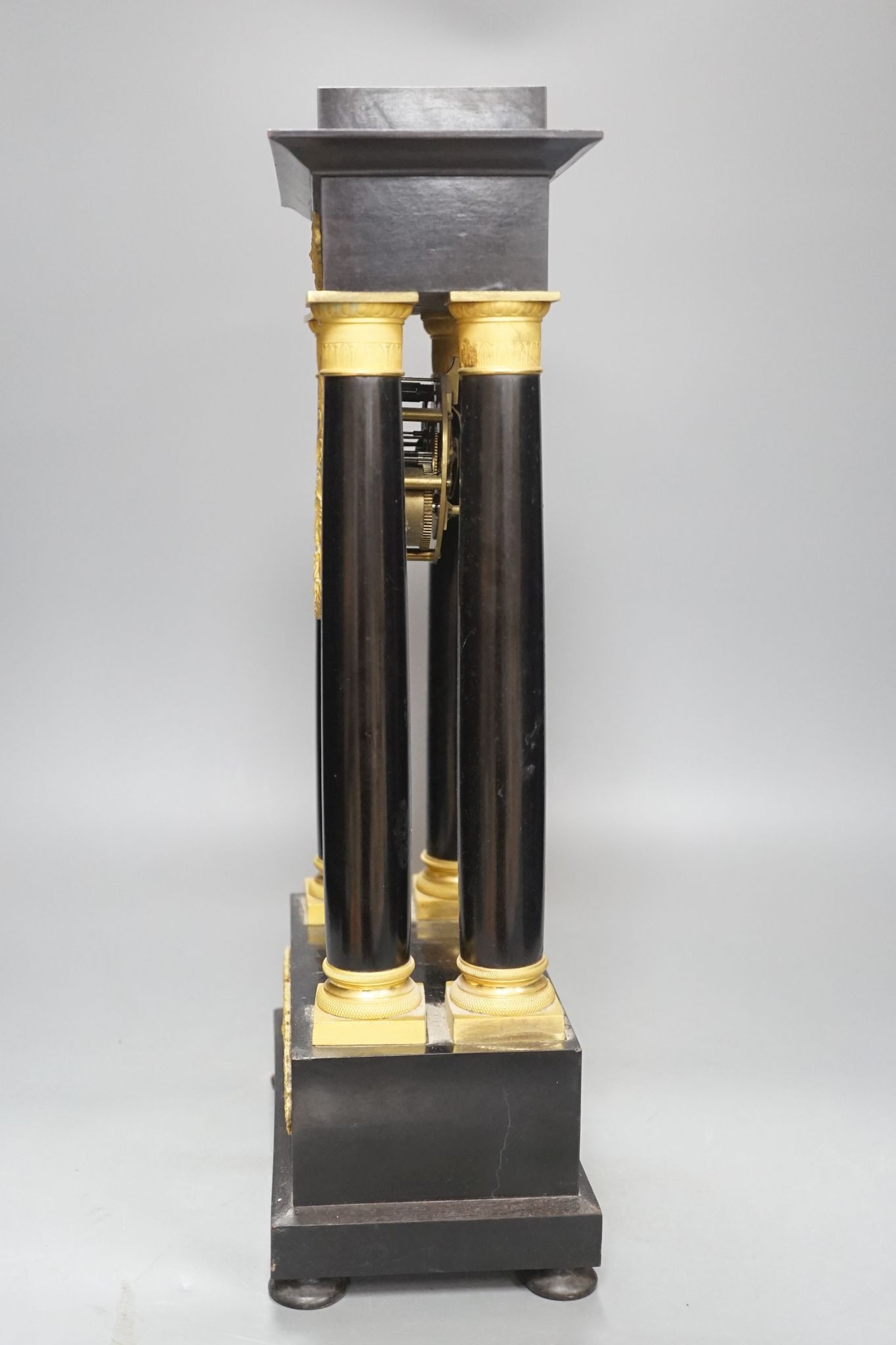 A 19th century French ebonised portico mantel clock with brass mounts, 47 cms high.